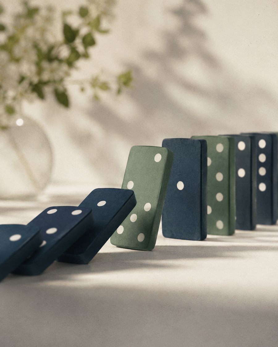 A row of dominoes mid chain-reaction, several fallen in sequence